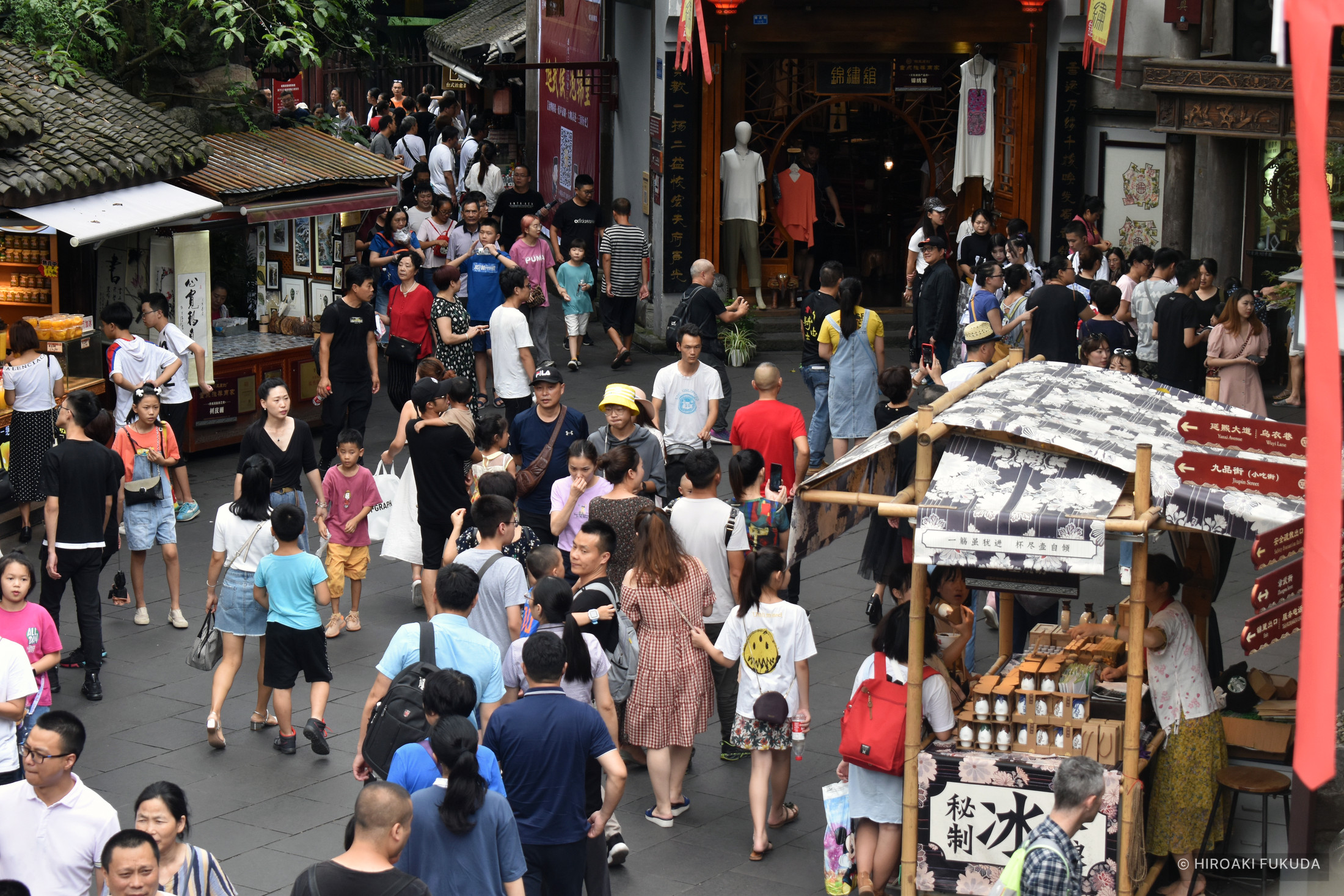 店が並ぶ通りを、多くの人々が行き交う写真