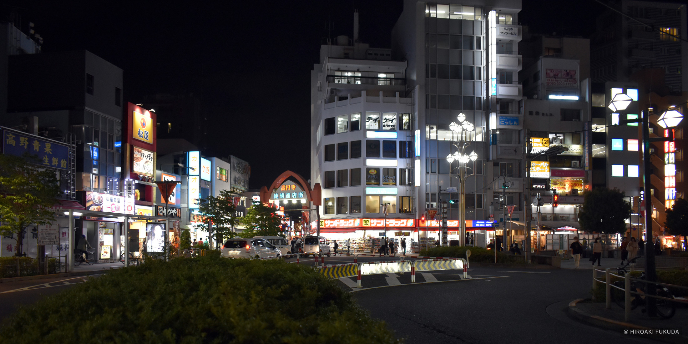 夜の街並み。明るい看板や街灯、商店街の入口が並ぶ写真